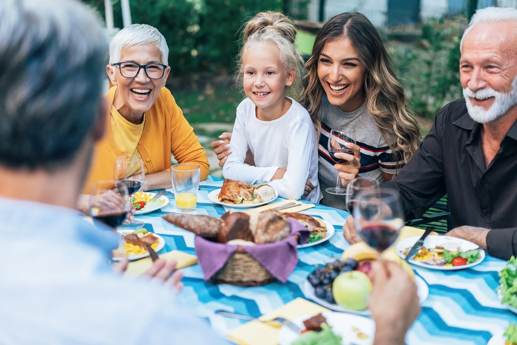 Multigenerational family sharing a meal together, smiling and enjoying each other's company